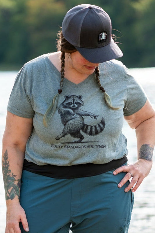 Person wearing a graphic t-shirt and blue pants standing in water with a natural background
