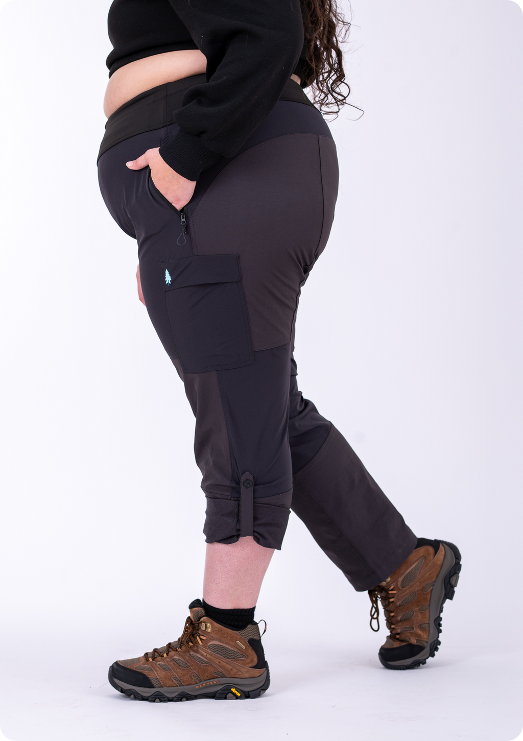 Person wearing black pants with a visible brand logo and brown hiking boots on a white background