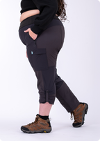 Person wearing black pants with a visible brand logo and brown hiking boots on a white background