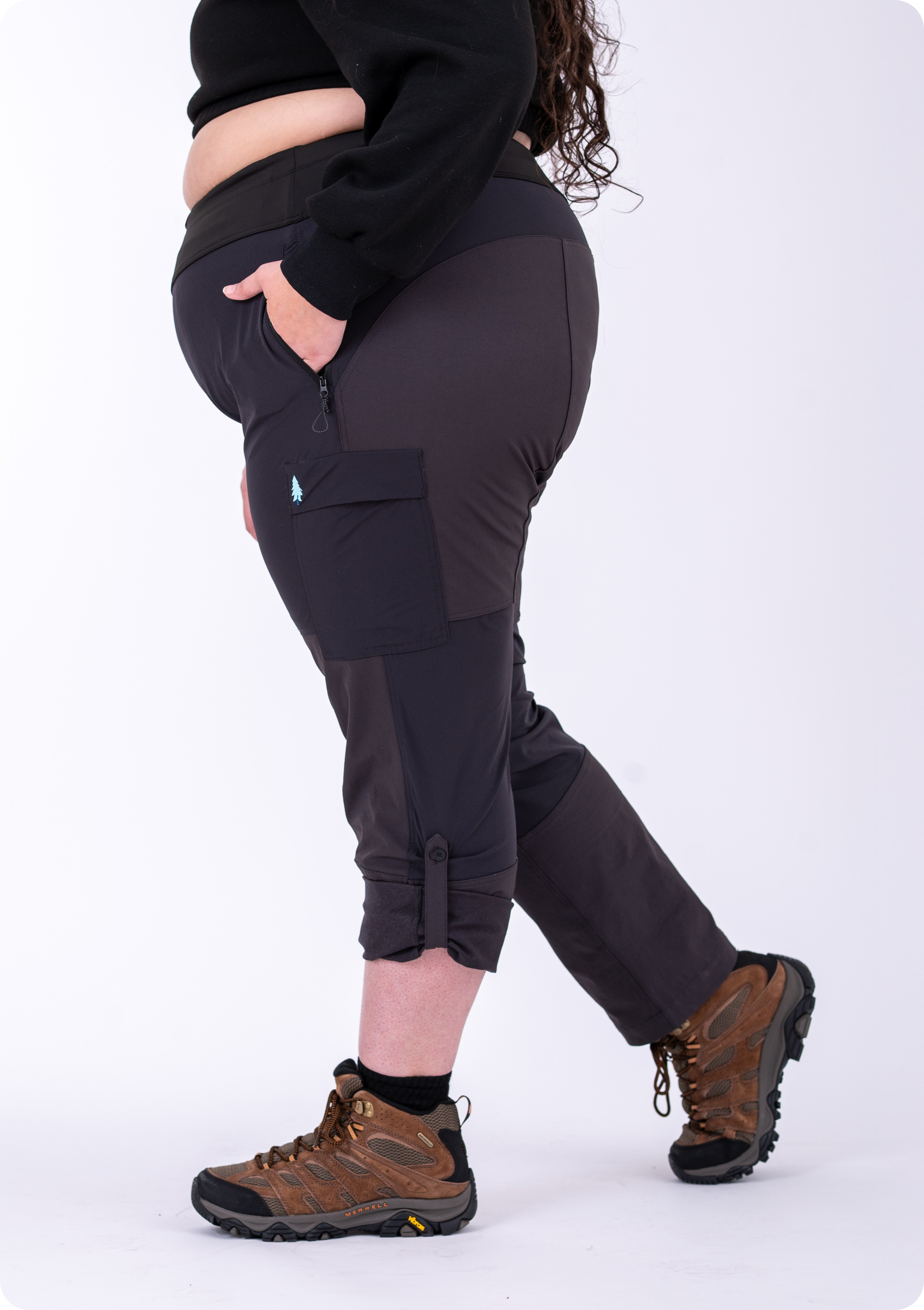Person wearing black pants with a visible brand logo and brown hiking boots on a white background