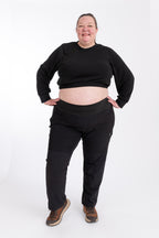 Person wearing black hiking pants and crop top on a white background