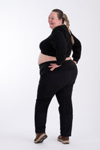Person wearing black hiking pants and crop top on a white background