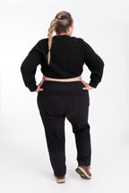 Person wearing black hiking pants and crop top on a white background