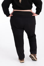 Person wearing black hiking pants and crop top on a white background