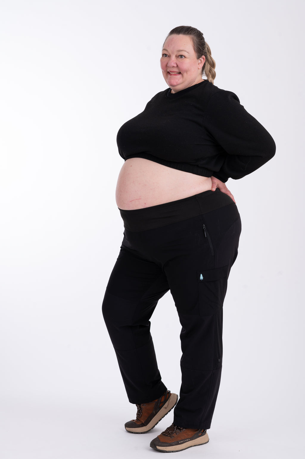 Person wearing black hiking pants and crop top on a white background