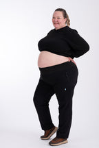 Person wearing black hiking pants and crop top on a white background