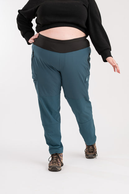 Person wearing teal pants and a black top on a white background