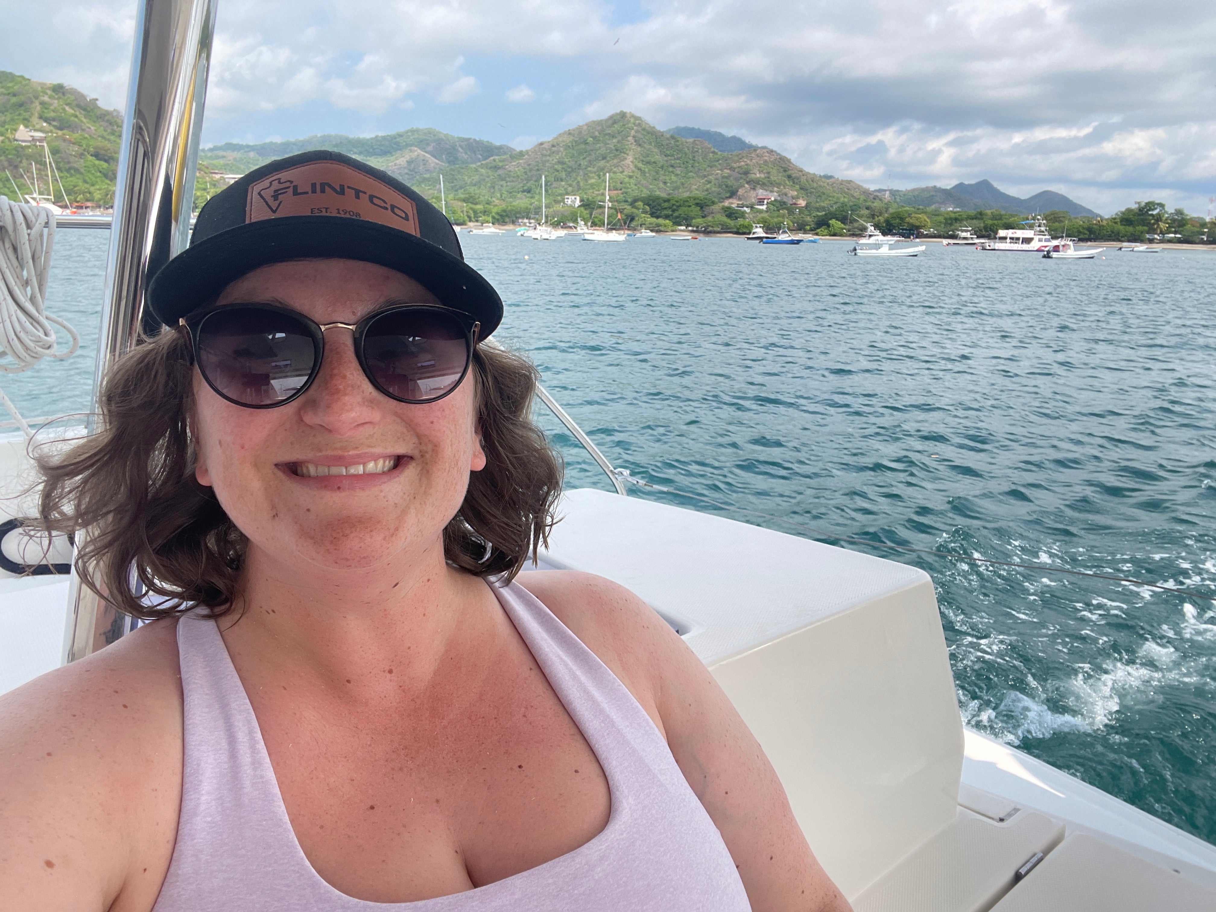 A woman on a boat with mountains behind her.