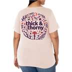 Person wearing a light pink t-shirt with 'thick & thorny' design on the back