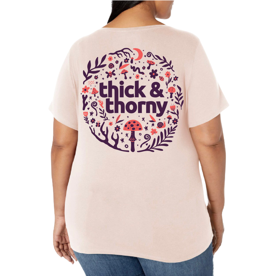 Person wearing a light pink t-shirt with 'thick & thorny' design on the back
