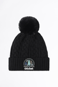 Black knit beanie with pom-pom and 'thicket' logo on a white background