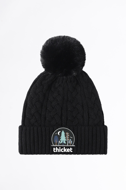Black knit beanie with pom-pom and 'thicket' logo on a white background