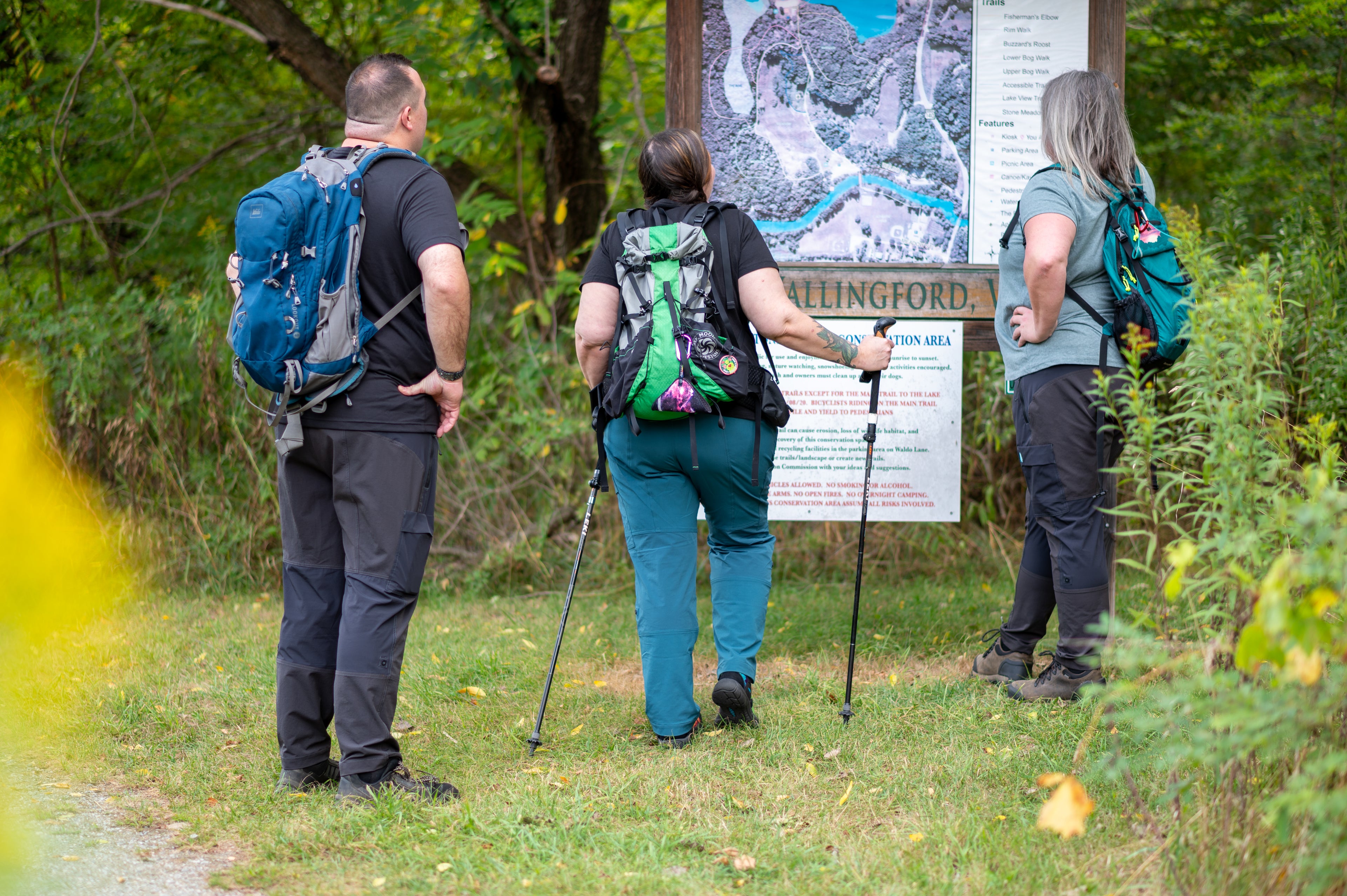 Three hikers with backpacks and maps in a forest setting