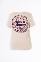 Light pink t-shirt with 'thick & thorny' graphic design on a white background